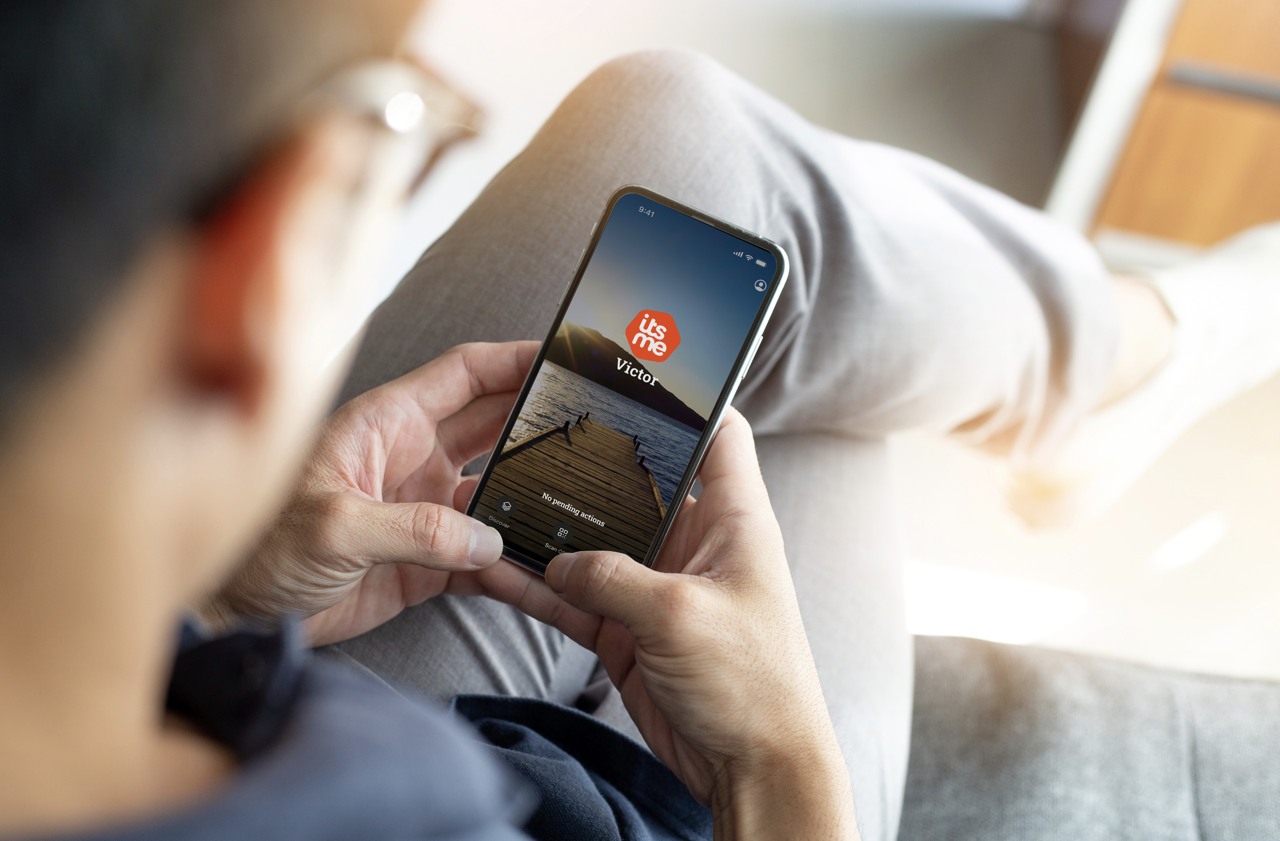 A man holding his phone with itsme app open