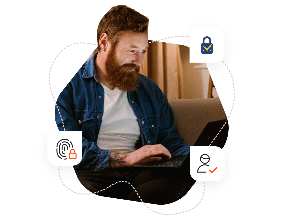 A man with a beard sitting on a sofa and typing on his laptop