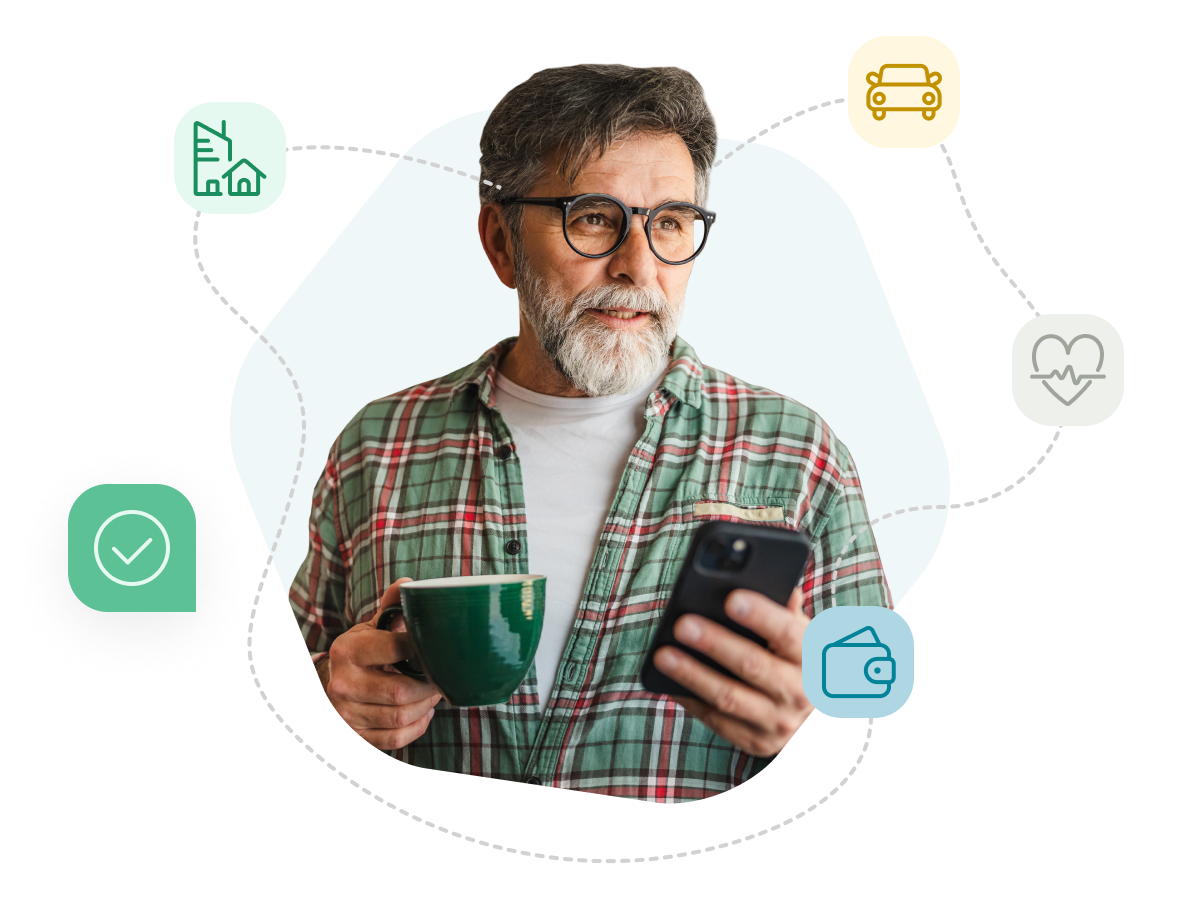 A man with round glasses and a beard, holding a cup of coffee and looking at his phone